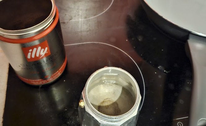 A moka pot and a tin of coffee on the stove